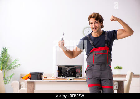 Young handsome contractor repairing fridge Stock Photo