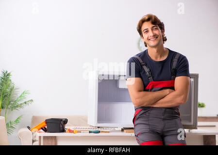 Young handsome contractor repairing fridge Stock Photo