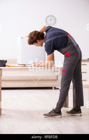 Young handsome contractor repairing fridge Stock Photo
