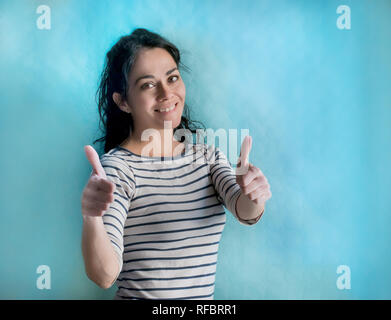 Brunette woman over isolated background doing happy thumbs up gesture with hands. Approving expression looking at the camera with showing success Stock Photo