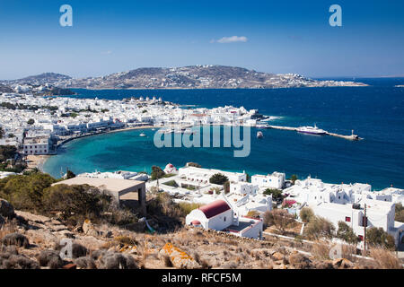 panoramic view of the Mykonos town harbor with famous windmills from the above hills on a sunny summer day, Mykonos, Cyclades, Greece Stock Photo
