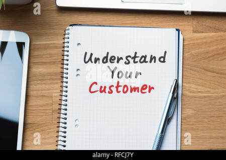 High Angle View Of Understand Your Customer Text Written On Spiral Notepad With Pen Stock Photo