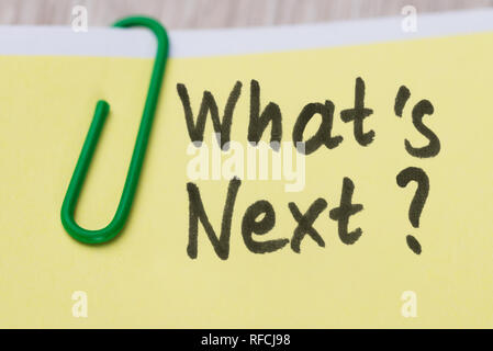 Close-up Of What's Next Text On Yellow Adhesive Notes With Green Paper Clip Stock Photo