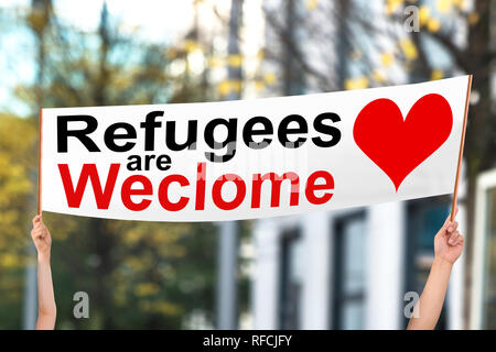 Close-up Of Two People Holding Refugees Are Welcome Banner At Outdoors Stock Photo