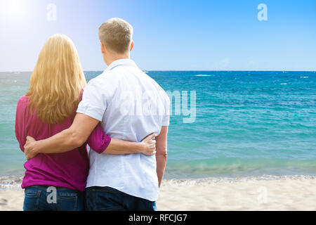 Rear View Of Mature Couple Standing At Tropical Beach Stock Photo