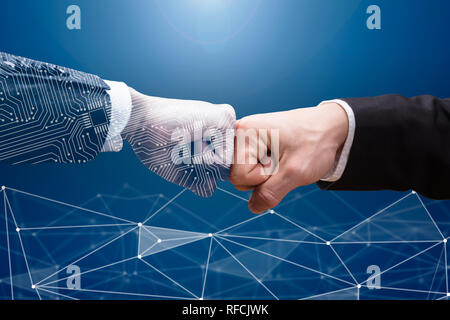 Close-up Of Digital Generated Human Hand And Businessman Making Fist Bump On Grey Background Stock Photo