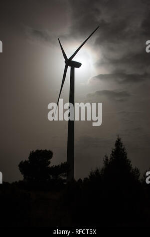 Windmill silhouette backlit on the field with sun rays through the clouds Stock Photo