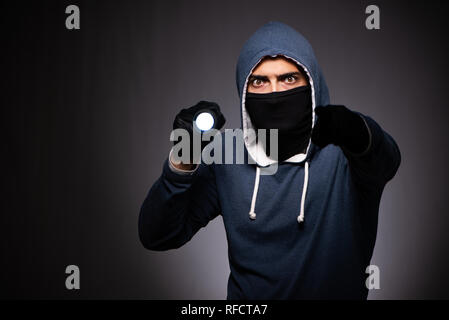 Young gangster in hood on grey background Stock Photo