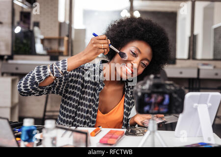 Pretty dark-skinned woman with bright makeup feeling amused Stock Photo