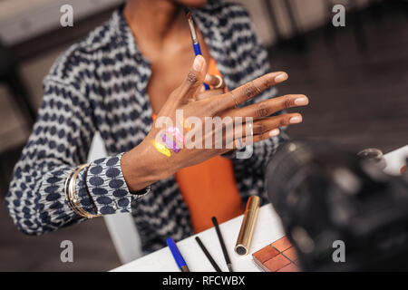 New colors. Dark-skinned african american woman wearing a gold bracelet showing new swatches Stock Photo