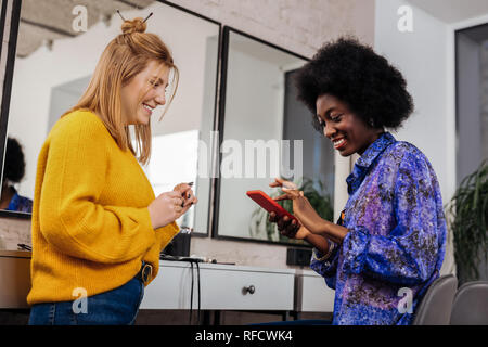 Beautiful dark-skinned stylist in an orange top writing a message Stock Photo