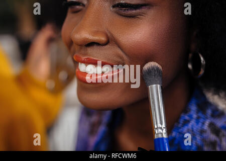 Pretty beaming dark-eyed model in an orange top smiling happily Stock Photo