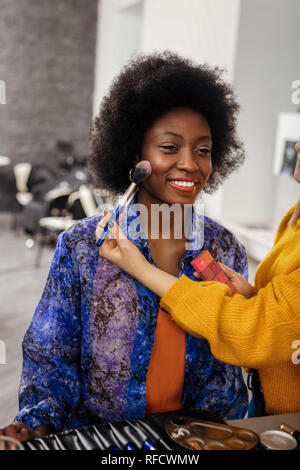 Pretty beaming dark-eyed model with curly hair smiling pleasantly Stock Photo