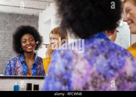 Cute beaming dark-eyed model and her stylist feeling wonderful Stock Photo