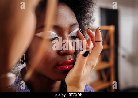 Fair-haired young stylist with black nail polish spending a day in fashion studio Stock Photo