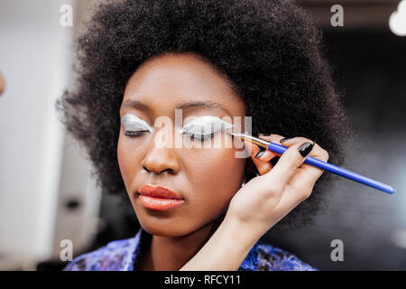 Dark-haired beautiful model with big earrings sitting silent Stock Photo
