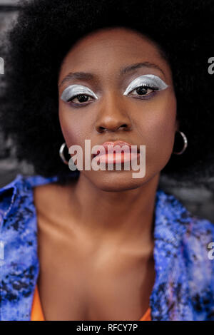 Dark-haired beautiful model with bright makeup looking thoughtful Stock Photo