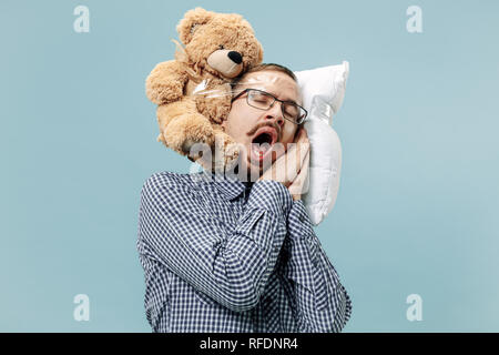 Tired man sleeping at home or office having too much work. Bored businessman with pillow and toy bear. The busy, boring, worried, be late, concerned, sleep day, introuble concept Stock Photo