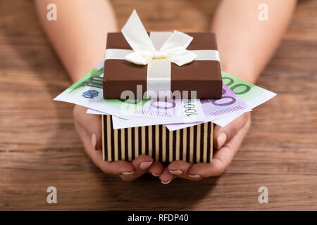Close-up Of Female's Hand Holding Gift Box Filled With Euro Notes With White Ribbon Bow Stock Photo