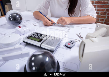 Close-up Of A Female Architect Drawing Blueprint With Pencil On Desk In The Office Stock Photo