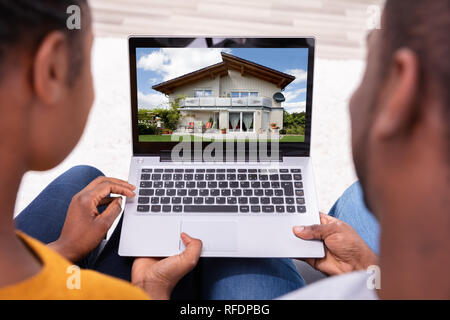 Close-up Of A Couple Looking At New House On Laptop Stock Photo