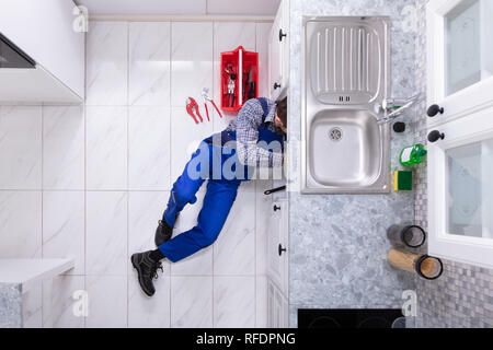 Young Male Plumber Repairing Sink Pipe With Adjustable Wrench Stock Photo