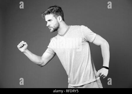 Man in tshirt and shorts on violet background. Runner in blue casual clothes on purple background. Sportsman in active wear for running. Sport fashion style and trend. Fitness and gym activity. Stock Photo