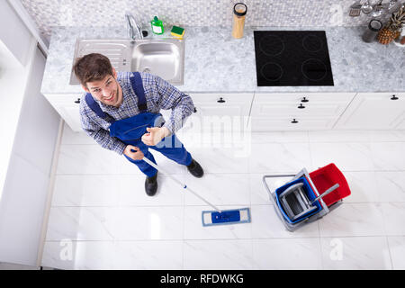 High Angle View Of Janitor Cleaning Floor With Mop In Kitchen Stock Photo