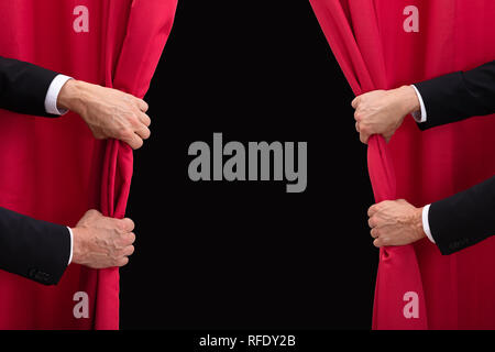 Close-up Of Two Men's Hand Opening Red Curtain Stock Photo