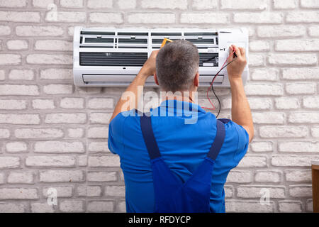 Male Electrician Checking Air Conditioner With Digital Multimeter Stock Photo