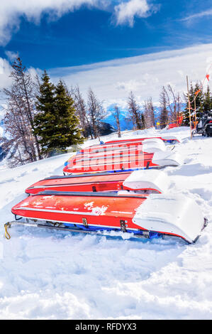 Rows of ski patrol toboggans or rescue sleds lie on snow on mountain ski resort. Also known as akia or emergency rescue sledg, it is used by mountain  Stock Photo