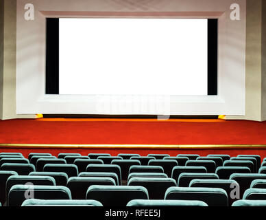 Empty rows of comfortable seats with big screen with white clipping path in cinema or theatre Stock Photo