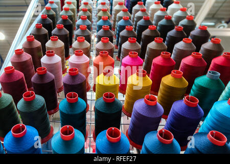 Colourful embroidery thread spool using in garment industry, row of multicoloured yarn rolls, sewing material selling in the market Stock Photo