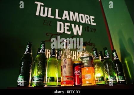 Kyiv, Ukraine - January 20, 2018: Tullamore Dew whiskey with Carlsberg beer bottles on the wooden shelf in bar with green walls. Stock Photo