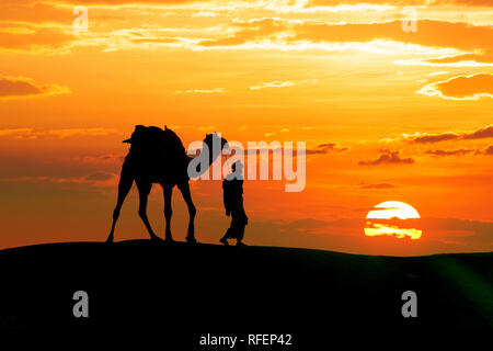 Walking with camel through Thar Desert in India, Show silhouette and dramatic sky Stock Photo