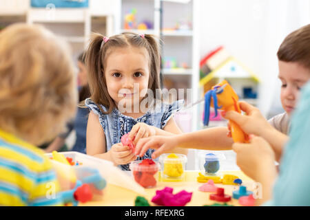 Group of kids playing with modeling clay in nursery Stock Photo