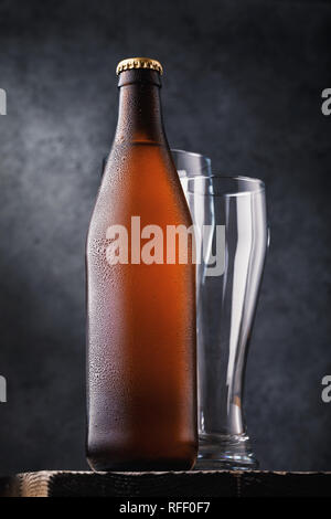 Bottle of light beer and two empty glasses on a wooden table Stock Photo