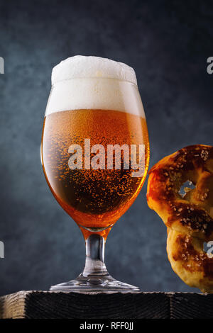 Full glass of filtered light beer with a pretzel, close-up Stock Photo