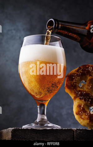 Glass filled with light filtered beer with a salty pretzel, close-up Stock Photo