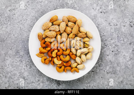 Nuts for beer in a white ceramic plate, top view Stock Photo