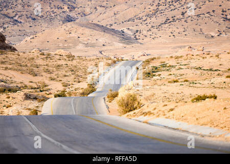 Kings highway, beautiful curvy road running through the Wadi Rum desert with hills in the distance in Jordan. Stock Photo