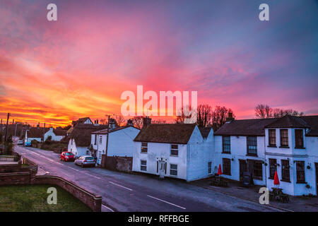 Dramatic and beautiful sunrise illuminating the sky over the quaint white cottages and terrace houses of Monkton, Kent, UK on a quiet winter morning. Stock Photo