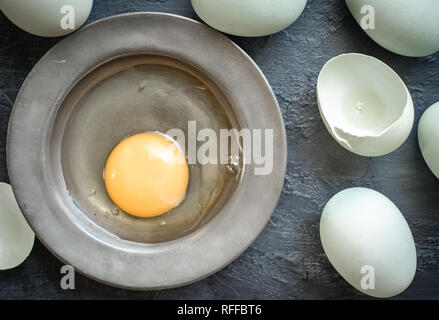 Eggs, raw flat lay, pewter dish, dark food Stock Photo
