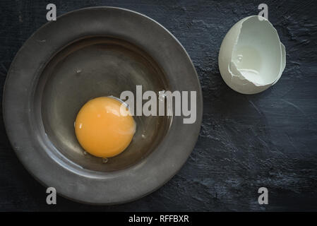 Eggs, raw flat lay, pewter dish, dark food Stock Photo