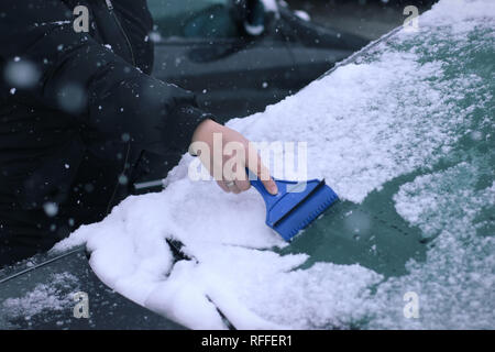 Female driver cleaning snow from windshield Stock Photo