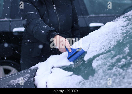 Female driver cleaning snow from windshield Stock Photo