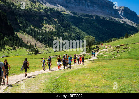 Hikers walking through valley of Ordesa National Park on a sunny day. Aragon, Spain Stock Photo