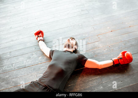 Beaten man lying on the floor of the boxing ring during the knockout Stock Photo