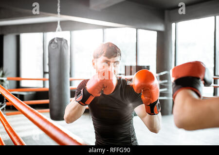 Two professional boxers in black sportswear during the fight on the boxing ring at the gym Stock Photo