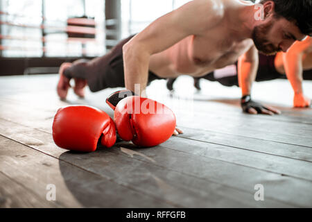 Two athletic men doing push-ups on the boxing ring, training before boxing at the gym Stock Photo